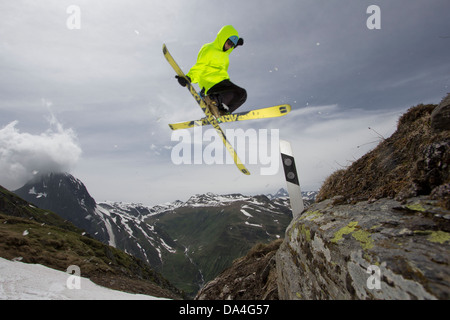 NUFENEN, VALAIS, SWITZERLAND. A freestyle freeskier is executing a trick on a handmade kicker to jump over a road marker. Stock Photo