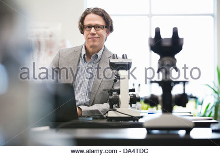 Portrait of male college professor leaning on table in science lab