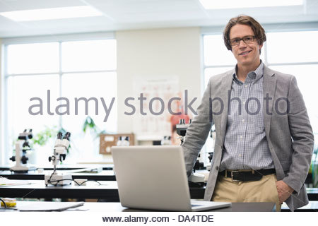 Portrait of male college professor with laptop standing in science lab