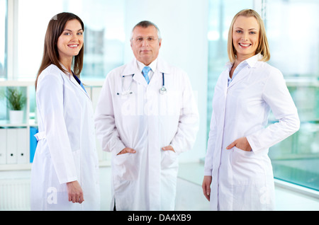 Portrait of happy nurses looking at camera with mature doctor behind Stock Photo