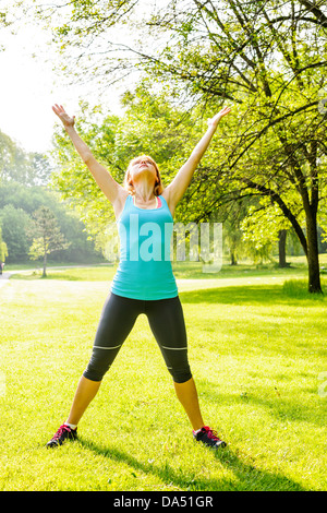Female fitness instructor stretching at green park in the morning Stock Photo