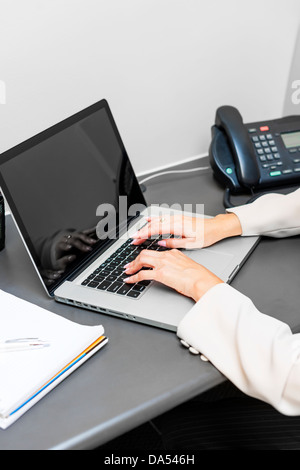 Female hands typing on laptop keyboard at office desk Stock Photo