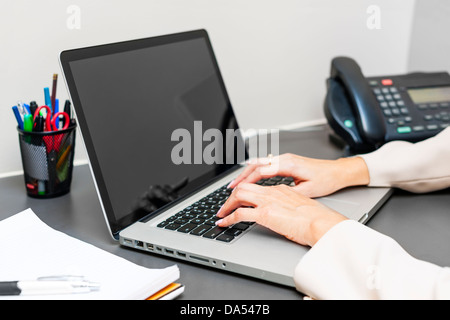 Female hands typing on laptop keyboard at office desk Stock Photo