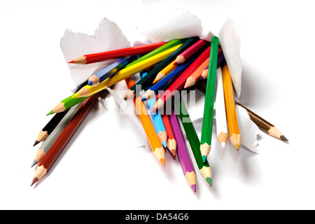 colored pencils breaking out from a teared white paper Stock Photo
