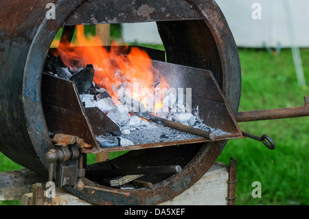 A metal bar is heated in a blacksmith's forge Stock Photo