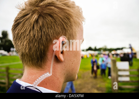 A young security guard wearing a coiled earpiece to listen to his two-way radio Stock Photo