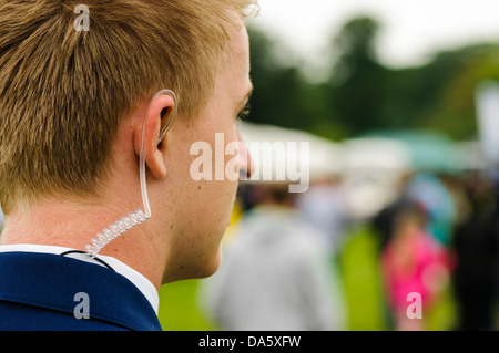 A young security guard wearing a coiled earpiece to listen to his two-way radio Stock Photo