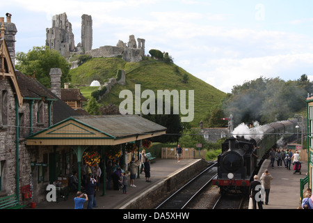 Corfe Castle railway station with castle in background and steam train arriving Stock Photo