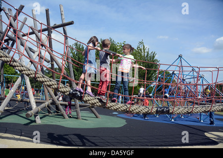 Three children, two girls and a boy, play on a rope walkway in an adventure playground Stock Photo