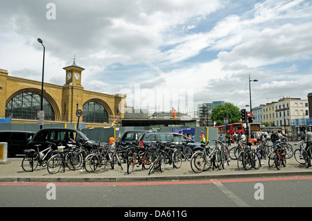 Bicycles attached to bike racks in front of taxis with King's Cross Station behind, London, England, UK Stock Photo