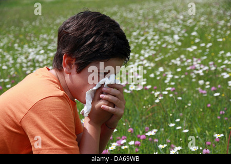 allergic child to pollen and flowers with a handkerchief while sneeze in the middle of the Minesweeper Stock Photo