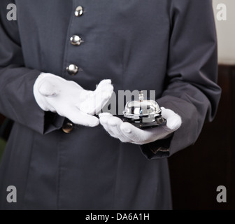 Bellboy holding bell in hotel on his hand Stock Photo