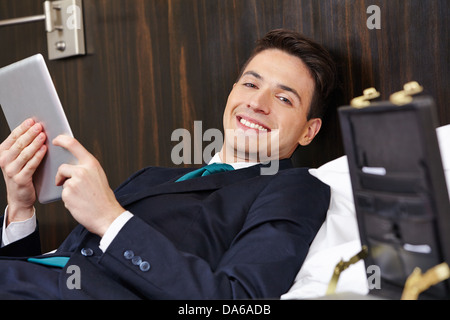 Smiling manager using a tablet computer in hotel room bed Stock Photo