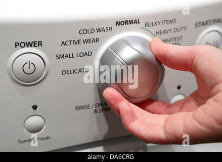 Hand turning on washing machine Stock Photo