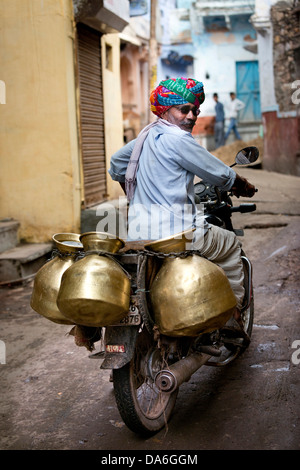Milkman riding a motorcycle with milk containers Stock Photo