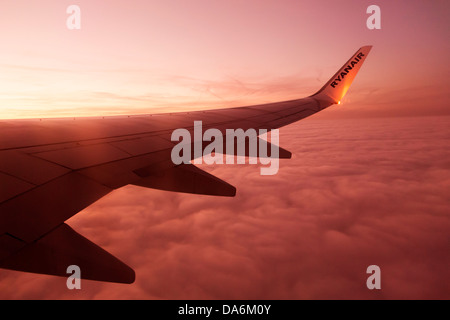 Wing of an airplane on cloud sky at dusk Stock Photo
