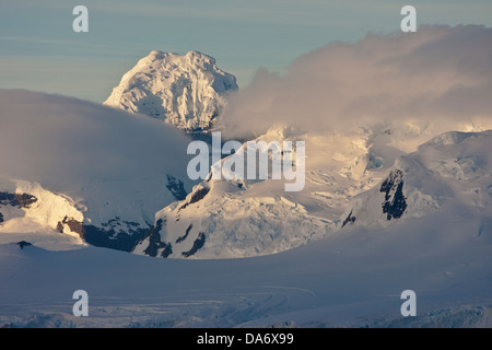 Fog layers around the mountains on the Antarctic Peninsula in the first morning light Stock Photo