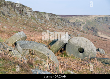 Millstones lie abandoned in situ at the old quarry site at Stanage Edge, overlooking Hathersage Moor, Peak District, UK Stock Photo