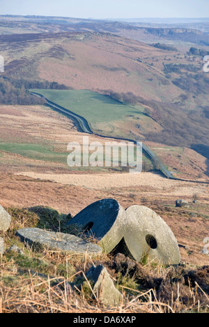 Millstones lie abandoned in situ at the old quarry site at Stanage Edge, overlooking Hathersage Moor, Peak District, UK Stock Photo