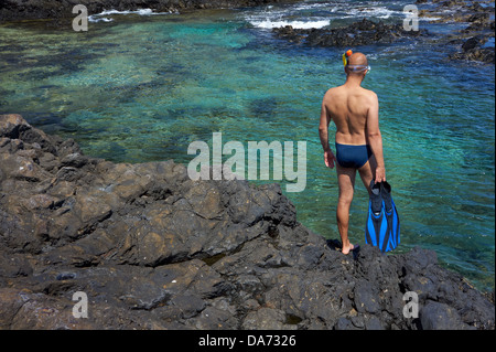 Young man with snorkeling equipment on the rock coast. Canary Islands, Lanzarote. Stock Photo