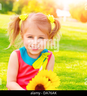 Adorable sweet child with sunflowers bouquet having fun in the garden, little girl enjoying summer nature, happiness concept Stock Photo