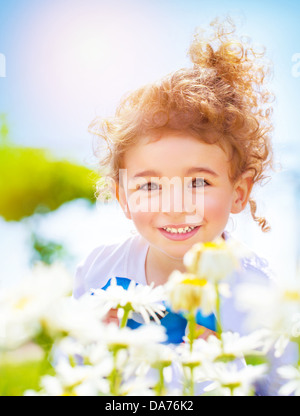 Closeup portrait of cute little boy having fun on daisy field, sweet child relaxing outdoors, happy summer holiday Stock Photo