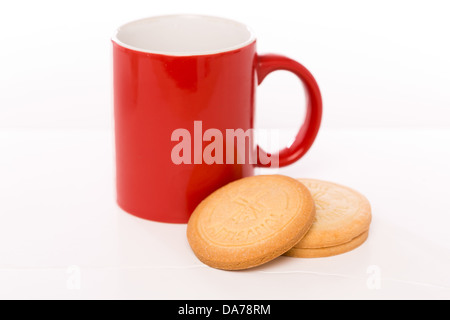 Red mug next to three biscuits Stock Photo