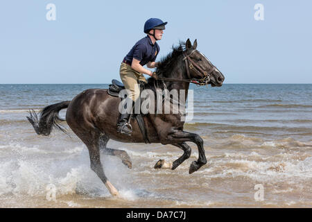 Holkham, Norfolk, UK. 4th July, 2013. The Household cavalry - A soldier of the Blues and Royals riding through the sea at Holkham beach in North Norfolk during their annual summer camp. Holkham. North Norfolk.England. 05 July 2013 Credit:  David Osborn/Alamy Live News Stock Photo