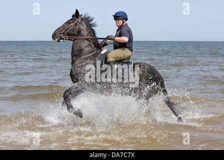 Holkham, Norfolk, UK. 4th July, 2013. The Household cavalry - A soldier of the Blues and Royals riding through the sea at Holkham beach in North Norfolk during their annual summer camp. Holkham. North Norfolk.England. 05 July 2013 Credit:  David Osborn/Alamy Live News Stock Photo