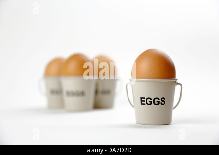 Four eggs in cups buckets one in foreground three in background Stock Photo