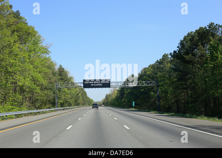 A large highway or road sign message on a US interstate in USA that says Texting while driving is illegal Stock Photo