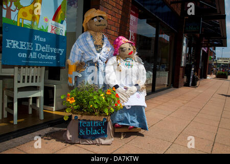 Furniture retailer Feather & Black store. Straw Man & woman advertising Free Delivery on all orders with two Scarecrows figures outside the shop, Wilmslow, The Scarecrow Festival that has again transformed the town – and provided a really fun event for families to enjoy. Stock Photo