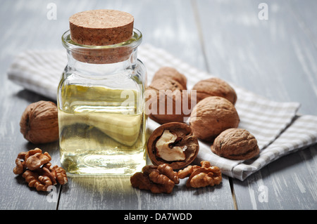 Walnut oil with nuts on a wooden background Stock Photo