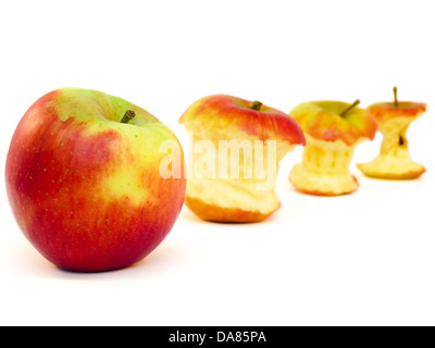 Four apples and apple cores lying diagonally on a white background Stock Photo