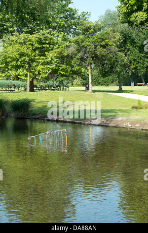 Sainsburys supermarket shopping trolley dumped in a lake in a UK public park Stock Photo