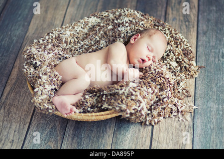 Newborn cute baby sleeping in wicker basket Stock Photo