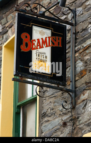 A sign on the outside of a pub advertises Beamish stout in an Irish village Stock Photo