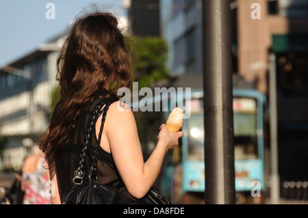 Summer in the city – Young woman with long brown curly hair eating a ice cream cone – Heilbronn Germany Stock Photo