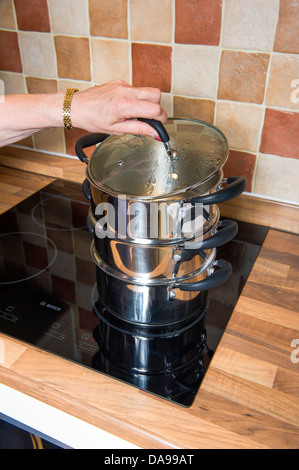 Multi level steamer, stainless steel on an induction hob. Stock Photo