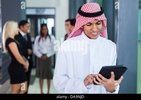 Saudi Arabian businessman using tablet computer in modern office Stock Photo