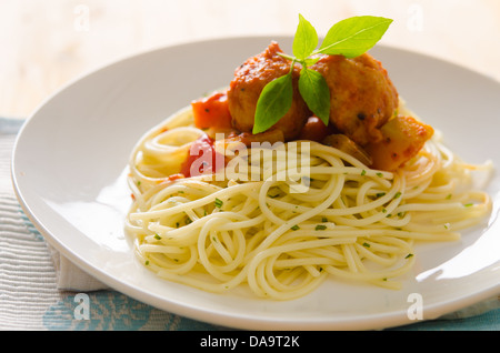 plate of spaghetti with meatballs in tomato marinara sauce and ingredients on a wooden table Stock Photo