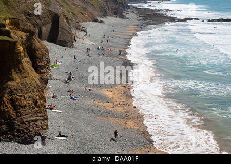 People on the beach of Sandymouth Bay, north Devon, England, as seen from adjoining cliffs overlooking the stretch of beach.