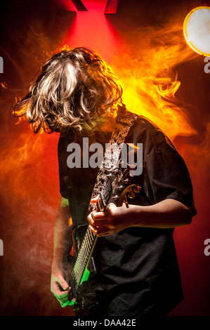 Unidentifiable young caucasian male musician playing guitar on stage. Stock Photo