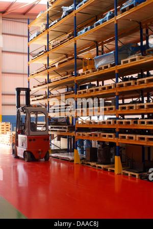 A a modern commercial warehouse with a fork lift truck and storage racks Stock Photo