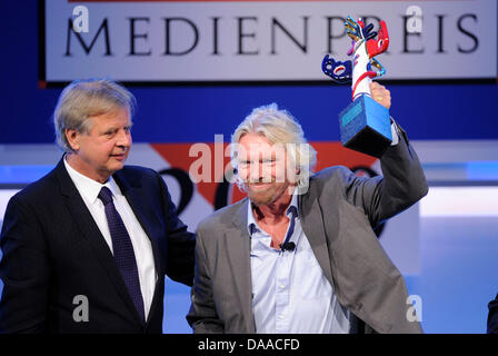 British enterpriser and billionaire Richard Branson is awarded with the German Media Prize 2010 at the Congress Center of Baden Baden, Germany, 24 January 2011. Despite his cruciate ligament rupture, he showed up on crutches to receive his prize. To his left stands media entrepreneur Karlheinz Koegel who founded the prize. Since 1992, the German Media Prize is awarded to a public f Stock Photo
