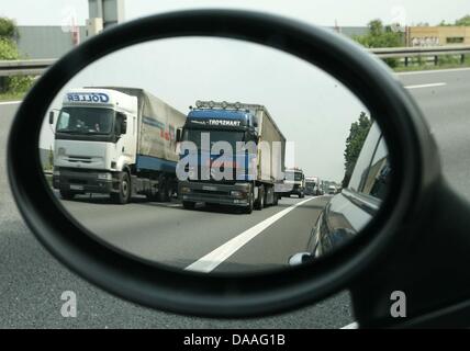 A file picture taken on 22 May 2007 shows two trucks during a overtaking manoeuvre in the rear view mirror of a car on a highway nearby Peine, Germany. So called 'elephant races' take place on Germany highways all the time. Two trucks drive next to each other for several minutes until one of them pulls over. An institutional speed limit, for which the truck drivers union called rec Stock Photo