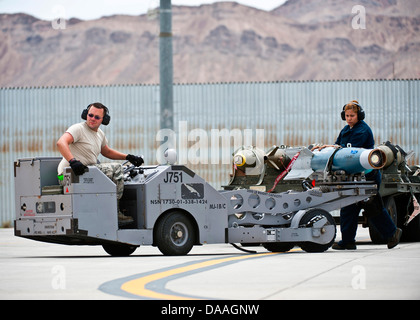 Airman 1st Class James Haddock and Staff Sgt. Lorena Hodge, 4th Aircraft Maintenance Squadron aircraft armament systems technicians, Seymour Johnson Air Force Base, N.C., transport a GBU-20 inert bomb during Green Flag-West 13-5 June 24, 2013, at Nellis A Stock Photo