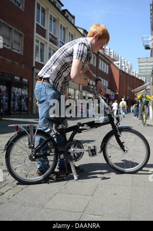 Employee Vincent Becker folds a bicycle from the municipal works in Muenster, Germany, 09 July 2013. The Muenster municipal works are renting foldable bicycles to their customers to connect all forms of public transportation from door to door. The bicycle can be used to cycle from home to the bus stop and then folded and take on the bus. Photo: CAROLINE SEIDEL Stock Photo