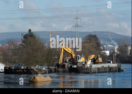 An excavator on a platform clears the Main Danube Canal from stones in Hausen, Germany, 22 January 2011. The canal was first covered with ice, then flooded and now it is filled with tons of stones. Therefore, it remains closed in the section between Bamberg and the sluce Hausen nearby Forchheim. Ships will be allowed to pass as early as the beginning of February. Photo: David Ebene Stock Photo