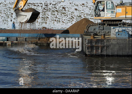 An excavator on a platform clears the Main Danube Canal from stones in Hausen, Germany, 22 January 2011. The canal was first covered with ice, then flooded and now it is filled with tons of stones. Therefore, it remains closed in the section between Bamberg and the sluce Hausen nearby Forchheim. Ships will be allowed to pass as early as the beginning of February. Photo: David Ebene Stock Photo